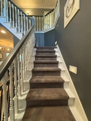 Clean carpeted staircase with white railings and painted walls in residential home