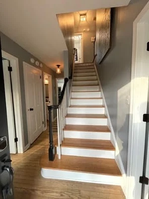 Clean wooden staircase with white risers and hallway with hardwood floors and white trim