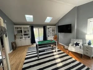 Clean living room with hardwood floors, striped rug, built-in shelving, and organized furniture
