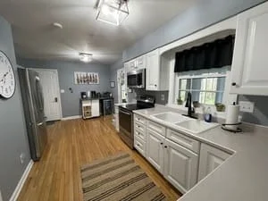 Clean kitchen with white cabinets, stainless steel appliances, and hardwood floors