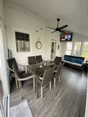 Clean living room with dining table, hardwood floors, windows, and ceiling fan after professional deep cleaning