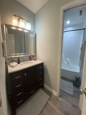 Clean bathroom vanity with dark wood cabinets, white sink, and polished mirror with lighting fixture