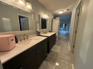 Clean master bathroom with dual vanity, dark cabinets, white countertops, and tile flooring