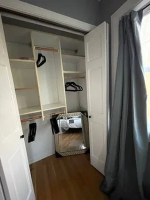 Organized walk-in closet with white shelving, hanging rods, and dark wood flooring