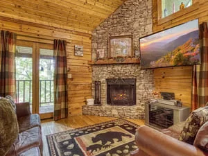 Clean log cabin interior with stone fireplace, wood beams, and furnished living room