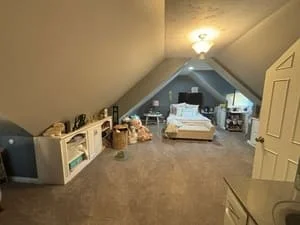Cleaned attic bedroom with organized furniture, clear carpeted floors, and organized storage items