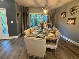 Clean dining room with hardwood floors, upholstered chairs, wooden table, and cleaned windows