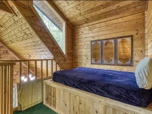 Clean log cabin bedroom with wooden walls, exposed beams, and organized built-in bed