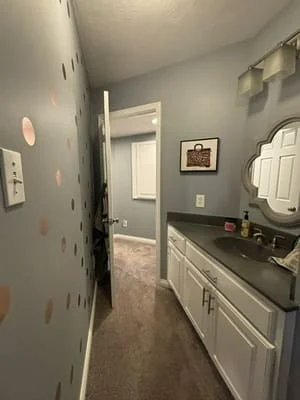 Clean bathroom vanity with white cabinetry, organized countertop, and freshly cleaned walls and mirror