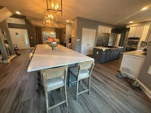Clean kitchen with white island, dining chairs, stainless steel appliances, and wood flooring